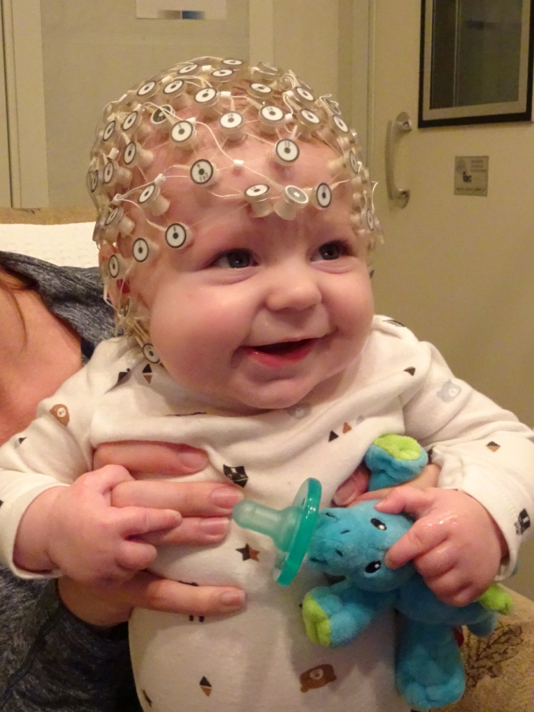 smiling baby wearing an EEG cap